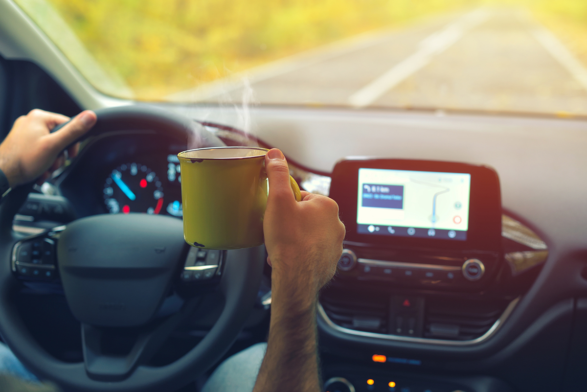 distracted driver drinking hot coffee from mug while driving